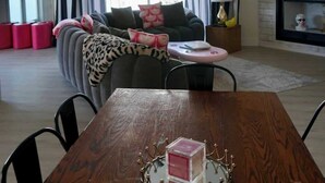 Un salon moderne avec une table à manger en bois, un canapé agrémenté de coussins à motifs, un lustre et une cheminée.