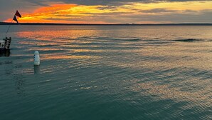 Une étendue d’eau calme, avec un coucher de soleil, un drapeau et une bouée.