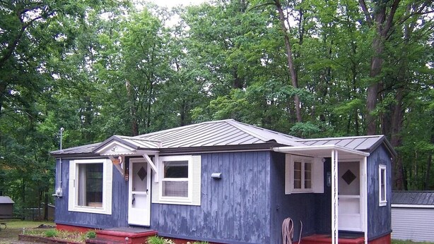 Une petite maison de plain-pied avec un porche, une porte d’entrée et une porte de garage.