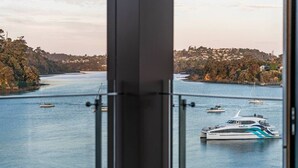 Un riu amb barques, una vista d'una població a l'altra banda de l'aigua, i un edifici amb barana de vidre.
