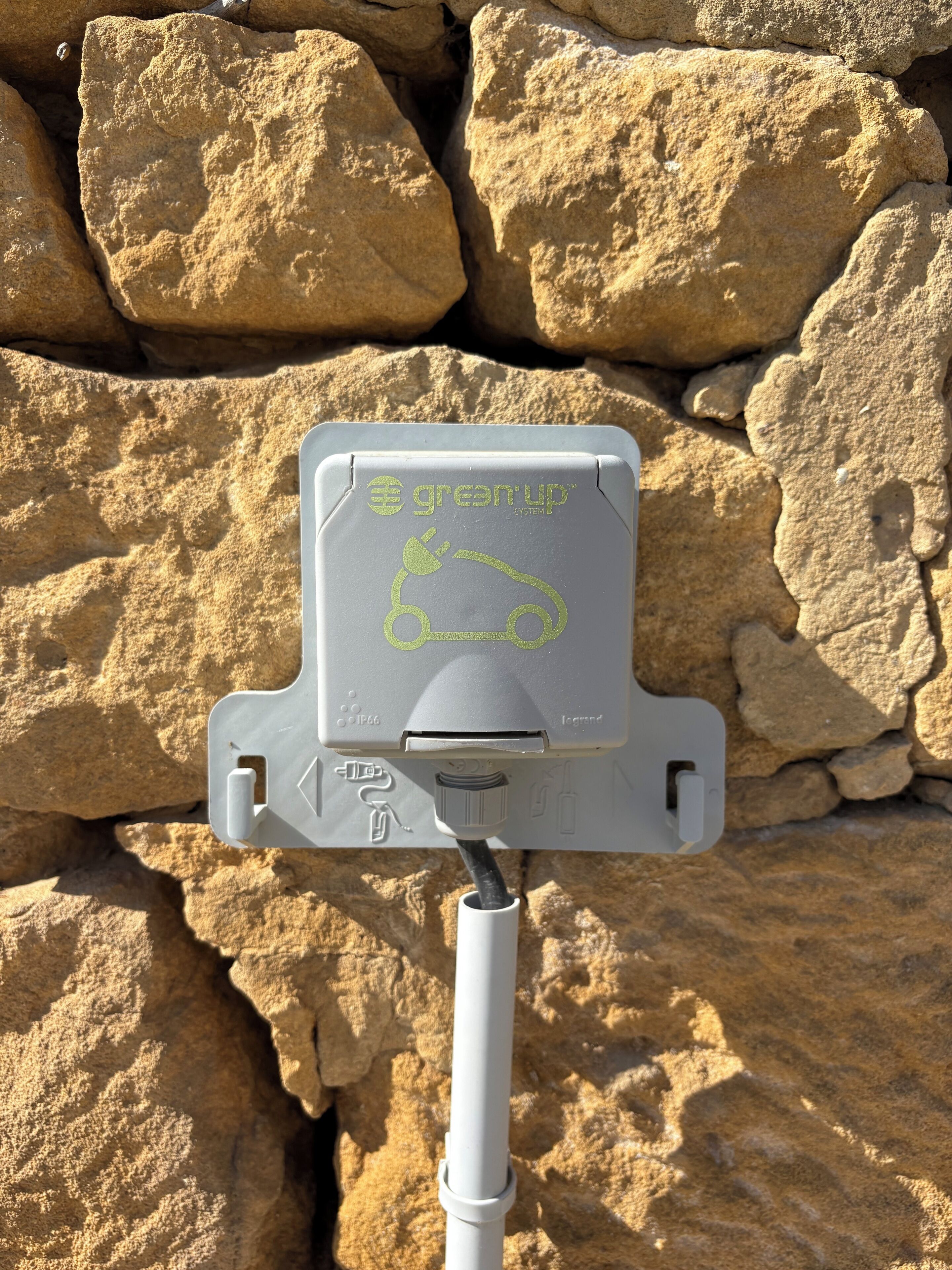 Une borne de recharge arborant le logo « greantup », ainsi qu’une prise et un câble.