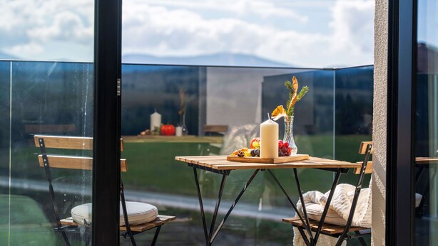 Une chambre avec vue sur les montagnes, une table avec une bougie, des fruits et un vase.