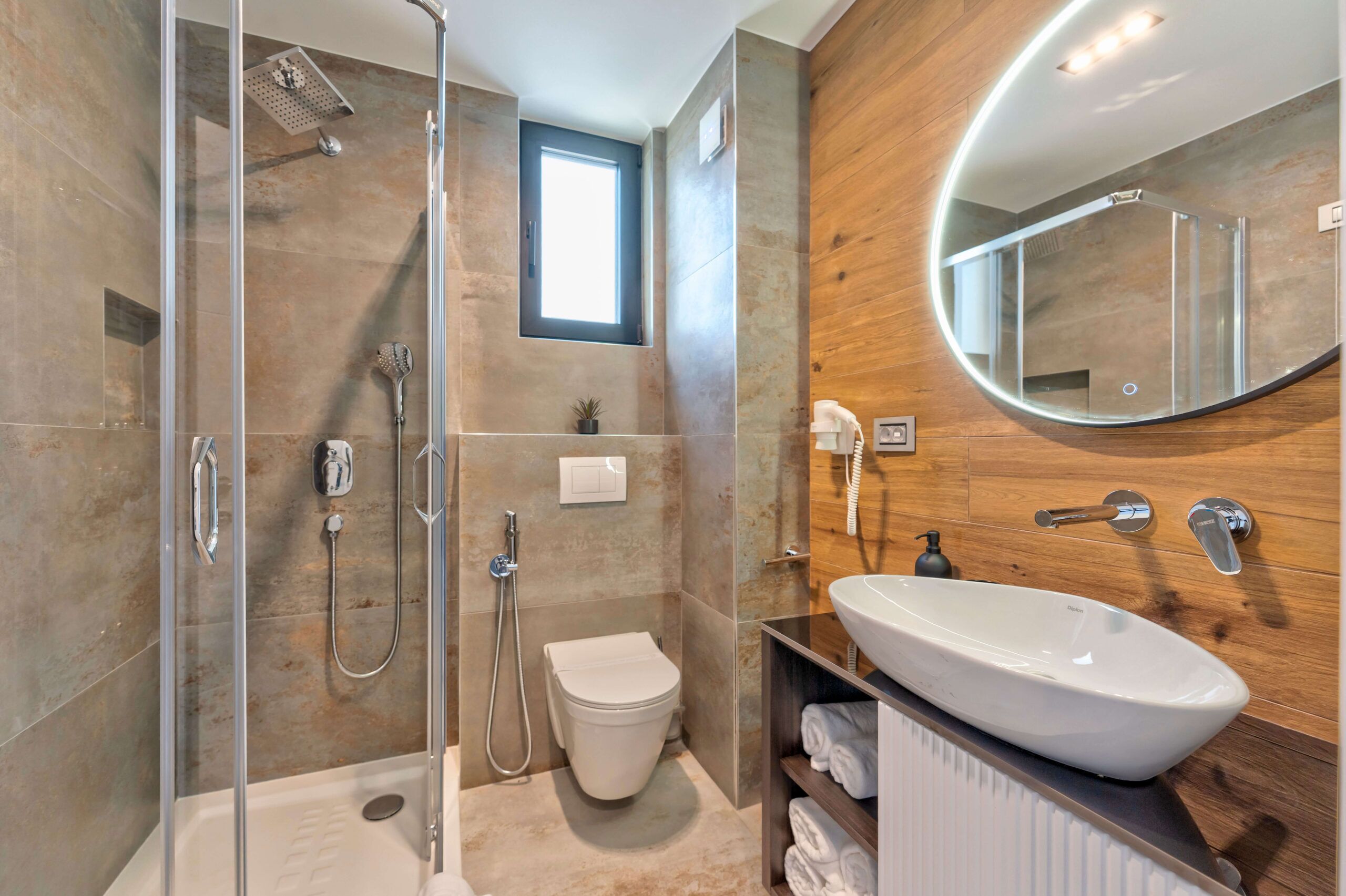 A modern bathroom with a glass-enclosed shower, a white sink, and a wooden vanity.