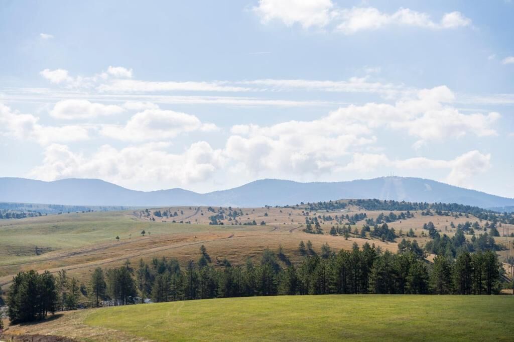 A panoramic view of a hilly landscape with a clear sky and distant mountains.