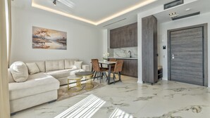 Un salon moderne comprenant un canapé, une table à manger et des chaises, un coin cuisine et une grande porte en bois.