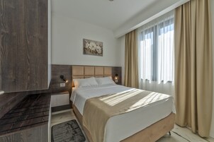 Una habitación de hotel con cama, mesita de noche, teléfono en la pared y un cuadro.