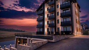 Un hôtel à plusieurs étages, doté de balcons, d’une entrée couverte et offrant une vue sur le paysage.