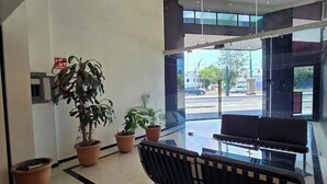 Un vestíbulo moderno con una recepción, plantas en macetas y un separador de vidrio.