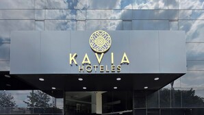 El exterior de KAVIA HOTELS con un diseño moderno, que presenta un gran logotipo sobre la entrada y un fachada de vidrio reflectante.