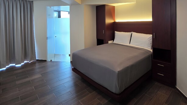 Una habitación de hotel moderna con una cama grande, suelo de madera y armarios empotrados.