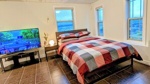 A bedroom with a bed, a TV, and a window.