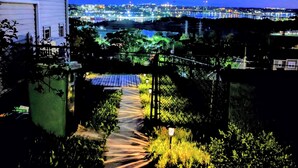 A pathway leading to a building with a view of a cityscape at night.
