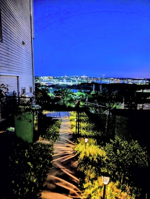 Un chemin menant à un bâtiment d’où l’on peut admirer la vue sur la ville illuminée la nuit.