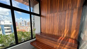 Un balcón con piso de madera y vistas a edificios de la ciudad.
