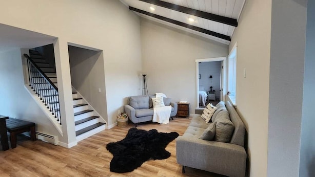 A spacious living area with a staircase, a grey sofa, a black rug, and a light-colored couch. - Jerry's Lake House Unit 1 on Denise Lake, Soldotna (Soldotna)