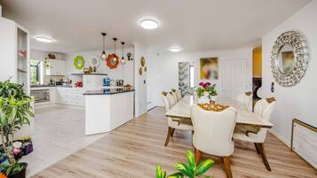 Une cuisine moderne avec des meubles blancs, un îlot central et des luminaires suspendus.