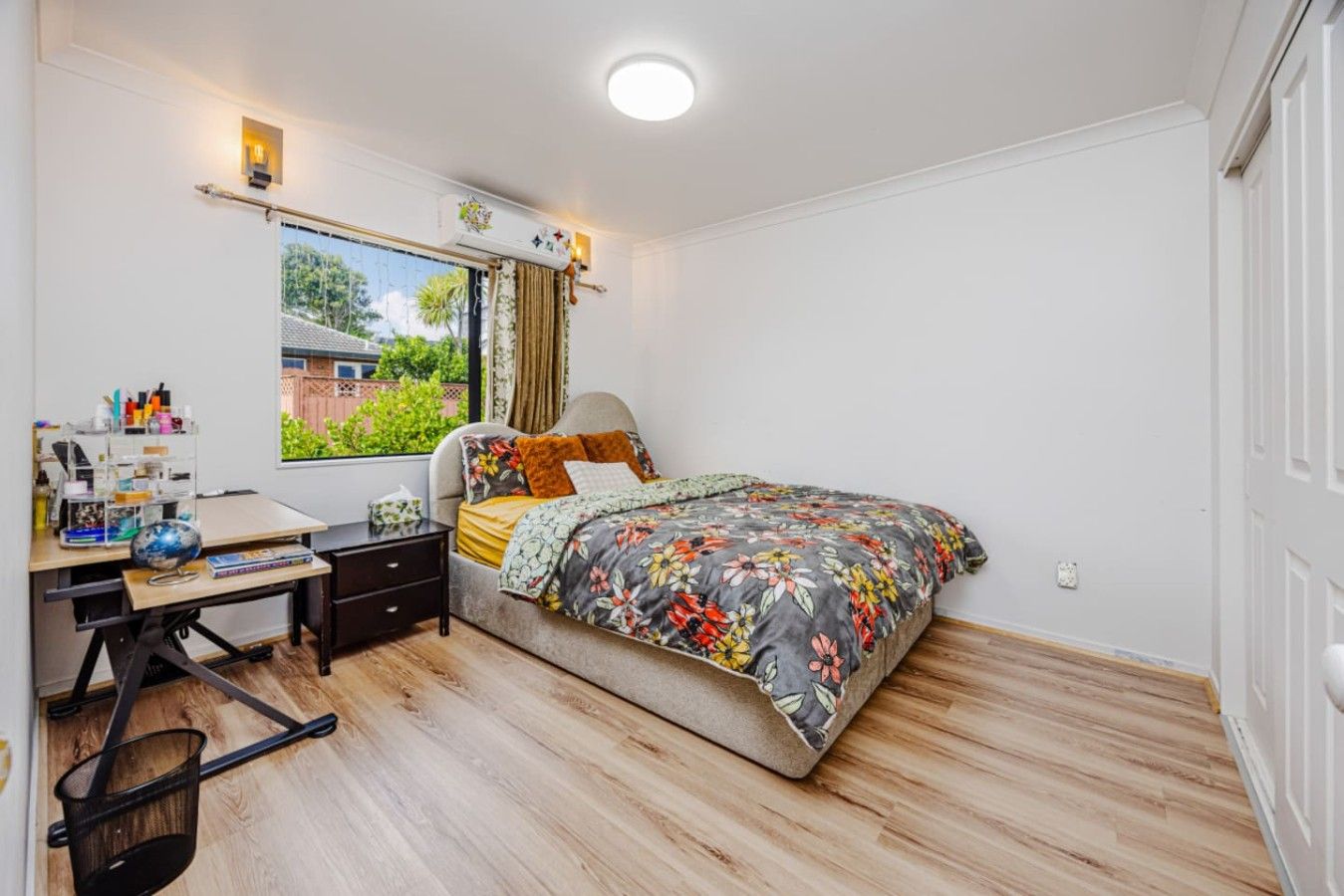 A bedroom with a bed, a desk, and a window.