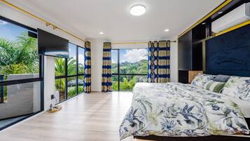 A bedroom with a large bed, a view of greenery, and a balcony.