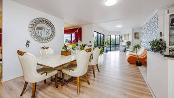 A modern dining area with a marble table, white chairs, and a decorative mirror on the wall.