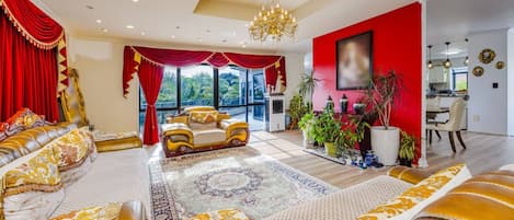 A luxurious living room with a large sofa set, a chandelier, and a view of the outdoors.