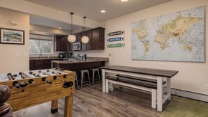 A modern kitchen with a foosball table, bar stools, a bench, and a world map on the wall. - Girdwood Mountain Basecamp-Sleeps 7-Near Alyeska (Anchorage)