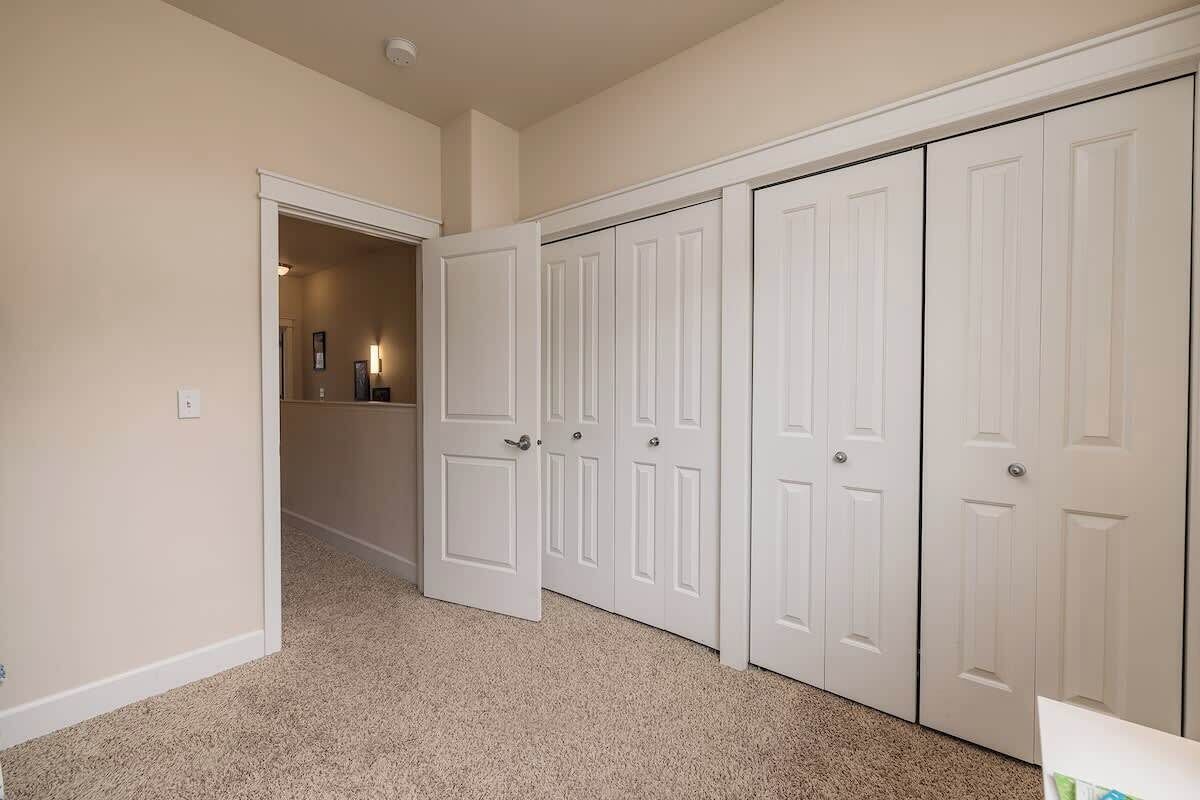 A hallway with beige carpet, white double doors, and a partially open door leading to another room.