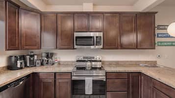 A kitchen with dark wood cabinets, stainless steel appliances, a granite countertop, and a dishwasher.