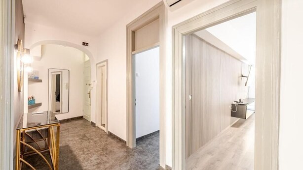 A hallway with a mirror, a vanity with a sink, and a door leading to a room with a bed. - Perfect 2-bedroom apartment with AC in charming Split (Split)