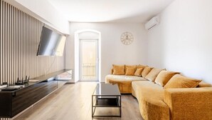 A modern living room with a sofa, a coffee table, a TV, and a clock on the wall. - Perfect 2-bedroom apartment with AC in charming Split (Split)
