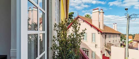 A balcony with a view of neighboring buildings, a clear sky, and a street lamp.