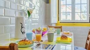 Ett frukostbord med olika rätter, en vas med en blomma och ett fönster med utsikt över byggnader.