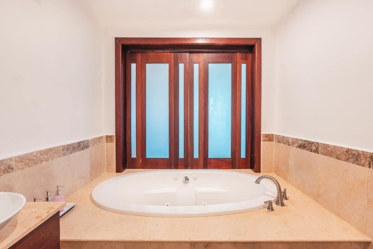 Ein Badezimmer mit einer großen Badewanne, zwei Waschbecken und einer Holztür mit gebürstetem Glas.