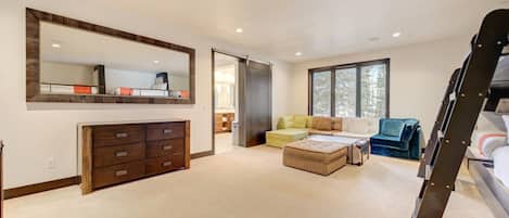 A spacious living room with a large mirror, a wooden cabinet, a sofa, a coffee table, and a staircase.