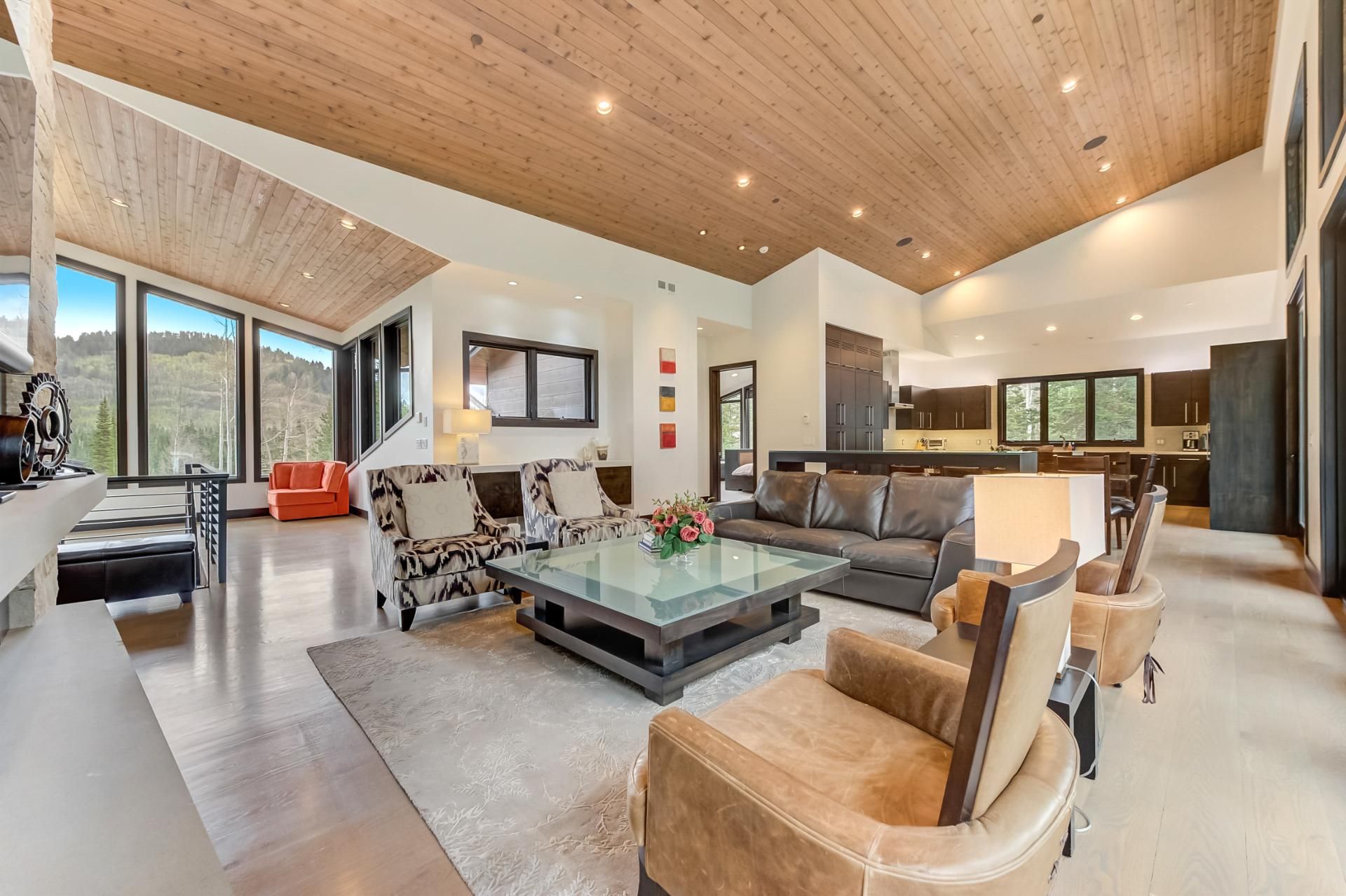 A spacious living area with a high ceiling, large windows, and a modern kitchen.