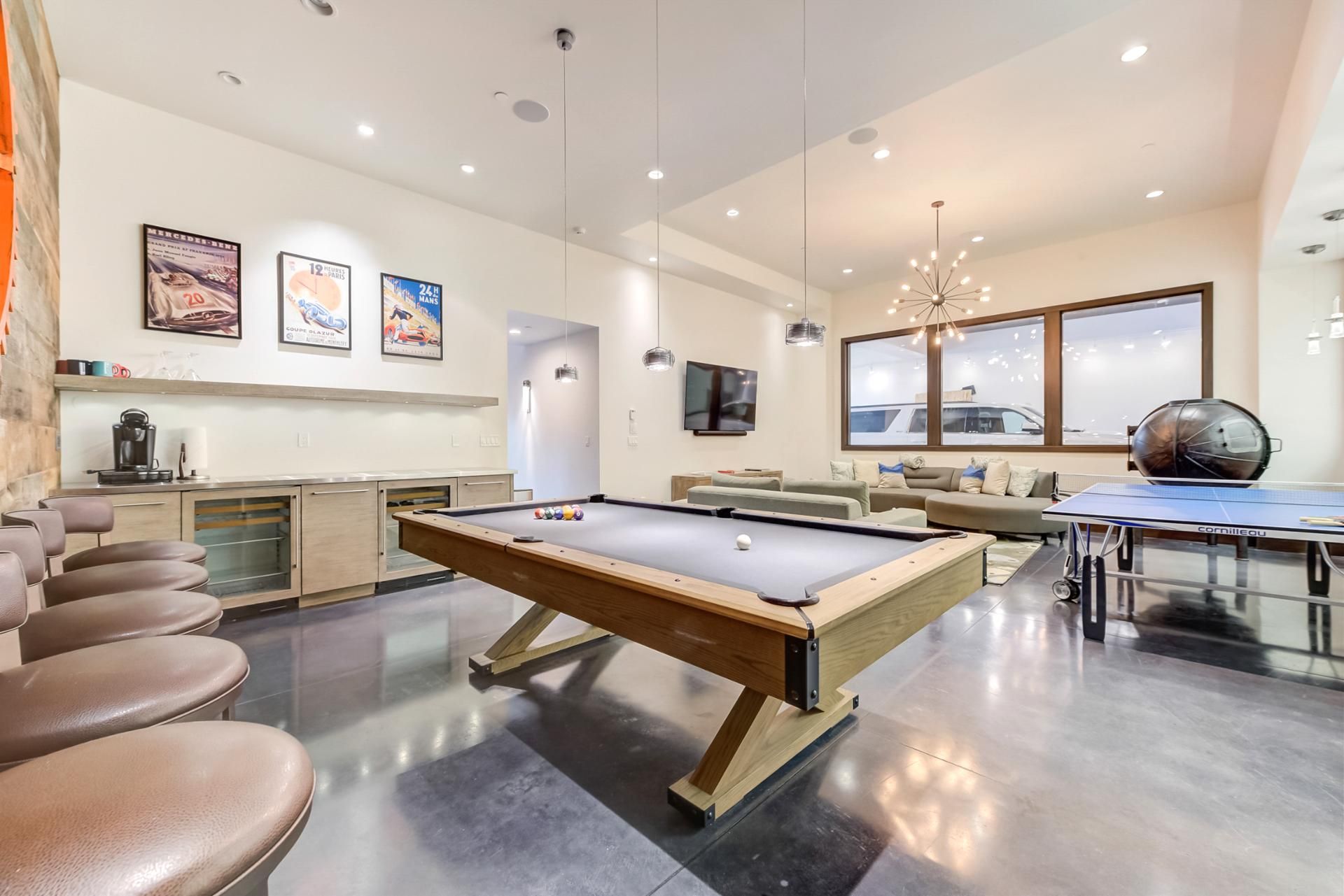 Un salon moderne doté d’une table de billard, de sièges confortables, d’un coin café et d’une grande fenêtre offrant une vue imprenable.