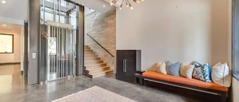 Ein modernes Interieur mit einer Treppe, einer Sitzecke mit Kissen und einem gemusterten Teppich.