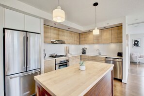 A modern kitchen with stainless steel appliances, a wooden island, and pendant lighting. - Yaletown Oasis (Vancouver)