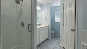 Une salle de bain équipée d’une douche, de toilettes et d’un lavabo, avec un carrelage décoratif et des murs bleu clair.