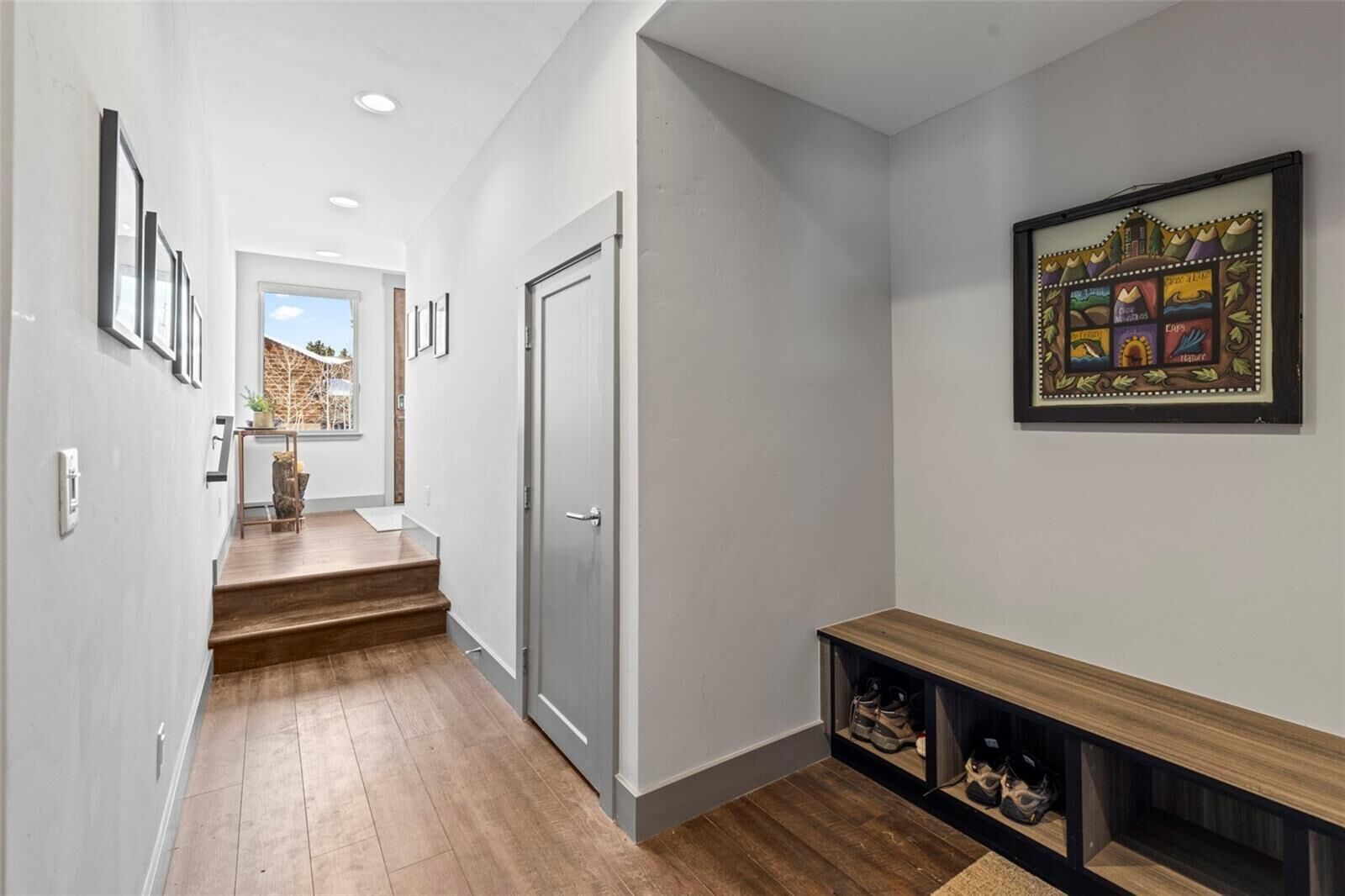 A hallway with a wooden bench, a door, and a framed picture on the wall.