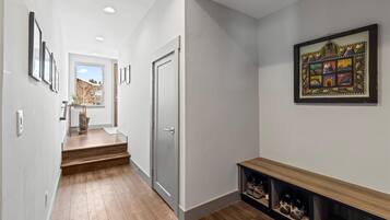 A hallway with a wooden bench, a door, and a framed picture on the wall.