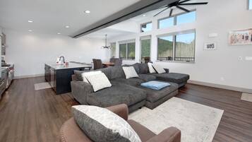 A modern living room with a sectional sofa, a dining area, and large windows.