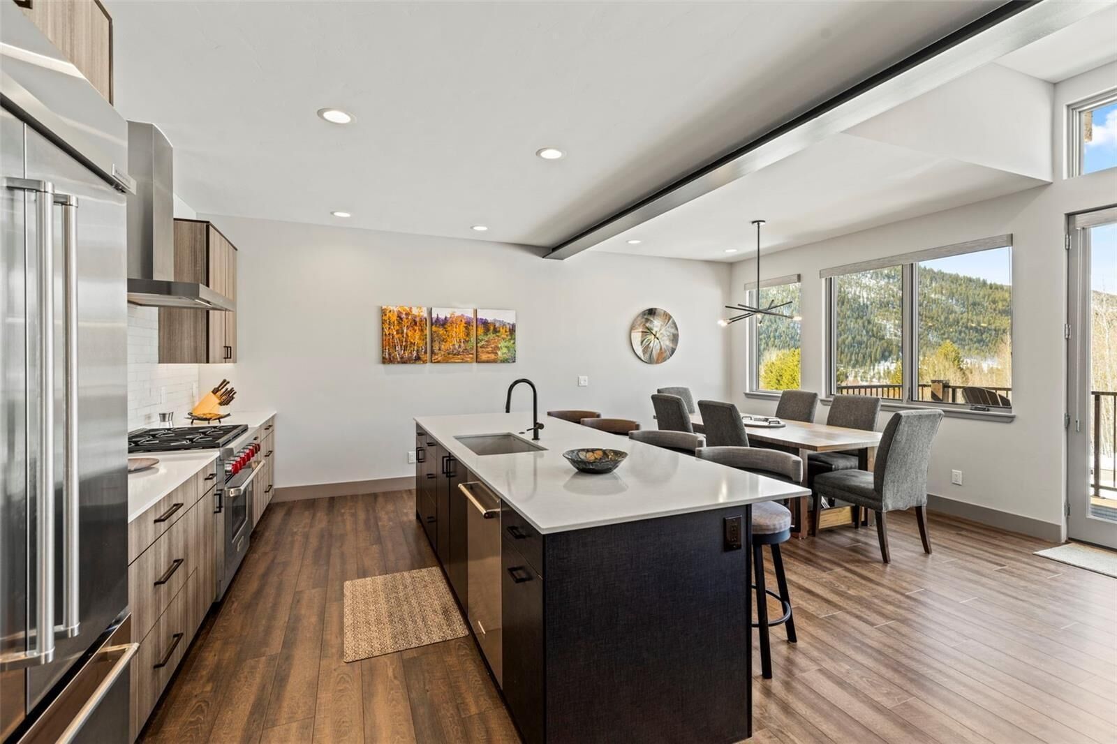Una cocina moderna con una isla central, armarios de madera y un comedor con vistas.