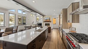 Een moderne keuken met een groot eiland, inbouwapparatuur en een eetgedeelte met uitzicht.
