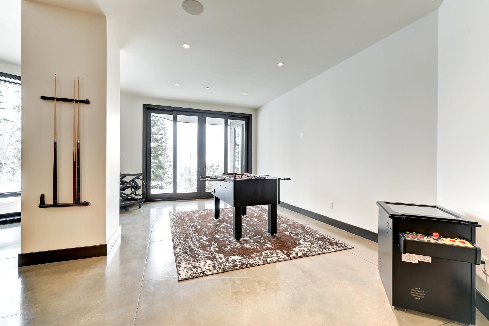 A modern room with a foosball table, a pool table, and a billiards rack.