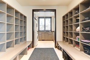 A walk-in closet with open shelving, a built-in washer and dryer, and a view through a doorway to a kitchen area. - KBM Resorts| Walk to Slopes, Sports Court, Private Home Theater, Sleeps 17, Outdoor Hot Tub PCO-184M (Park City)