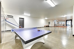 A ping pong table in a spacious room with a door, a window, and exercise equipment in the background. - KBM Resorts| Walk to Slopes, Sports Court, Private Home Theater, Sleeps 17, Outdoor Hot Tub PCO-184M (Park City)