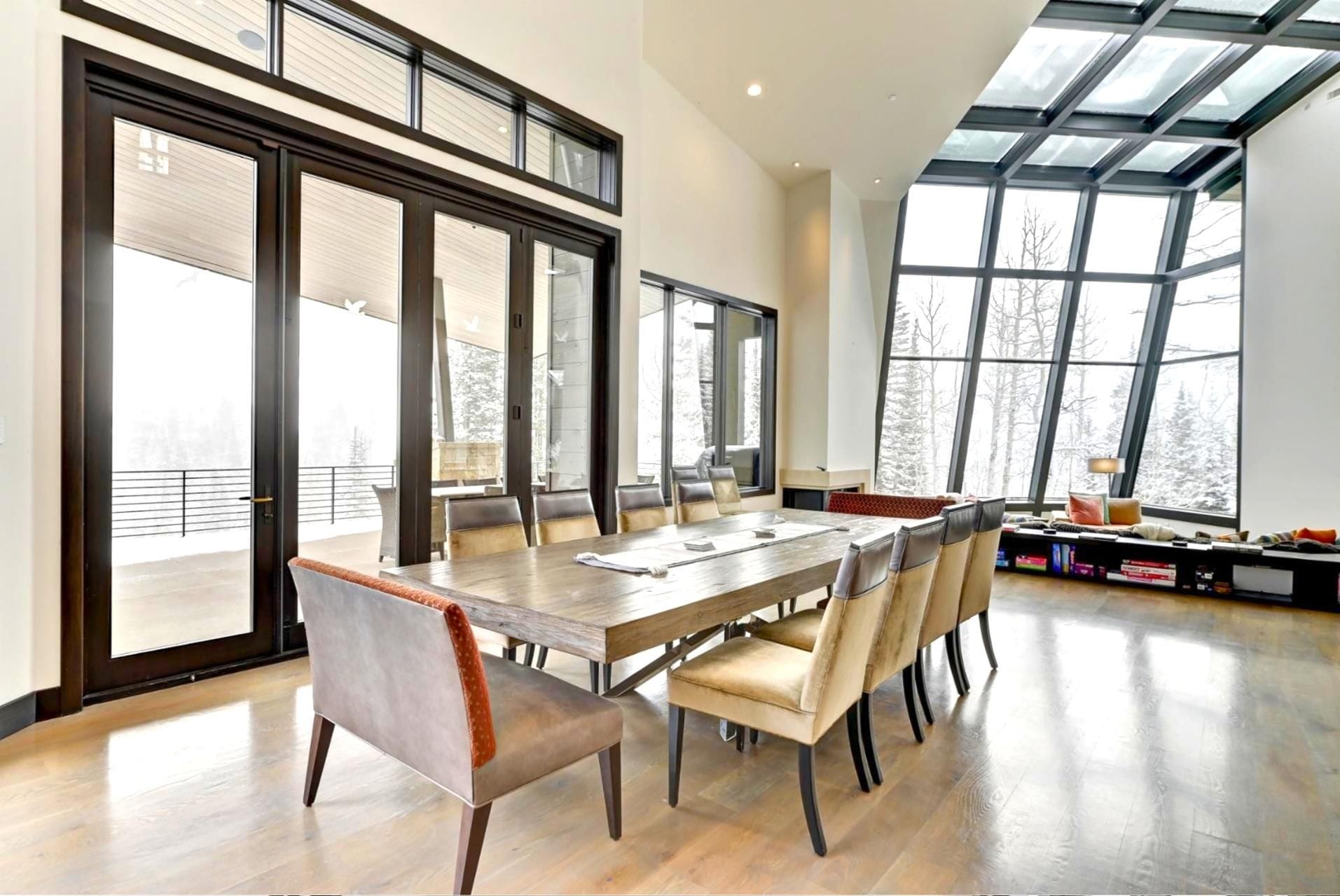 Un comedor moderno con una gran mesa y sillas, ventanas amplias y vistas al exterior.