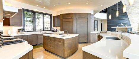 A modern kitchen with a central island, built-in appliances, and a large window providing natural light.
