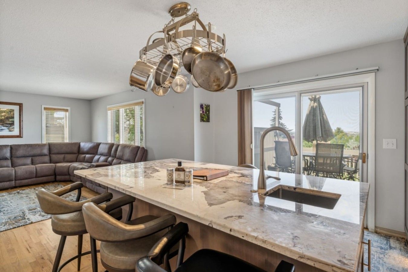 A modern kitchen with a large island, bar stools, and a view to the outdoors.