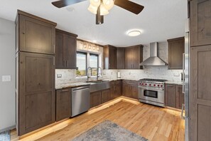 A kitchen with wooden cabinets, a stainless steel dishwasher, a gas stove, and a ceiling fan.